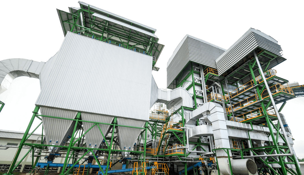 The image shows a large industrial facility with a complex structure, featuring multiple levels of piping, staircases, and platforms, predominantly in green and white colors.