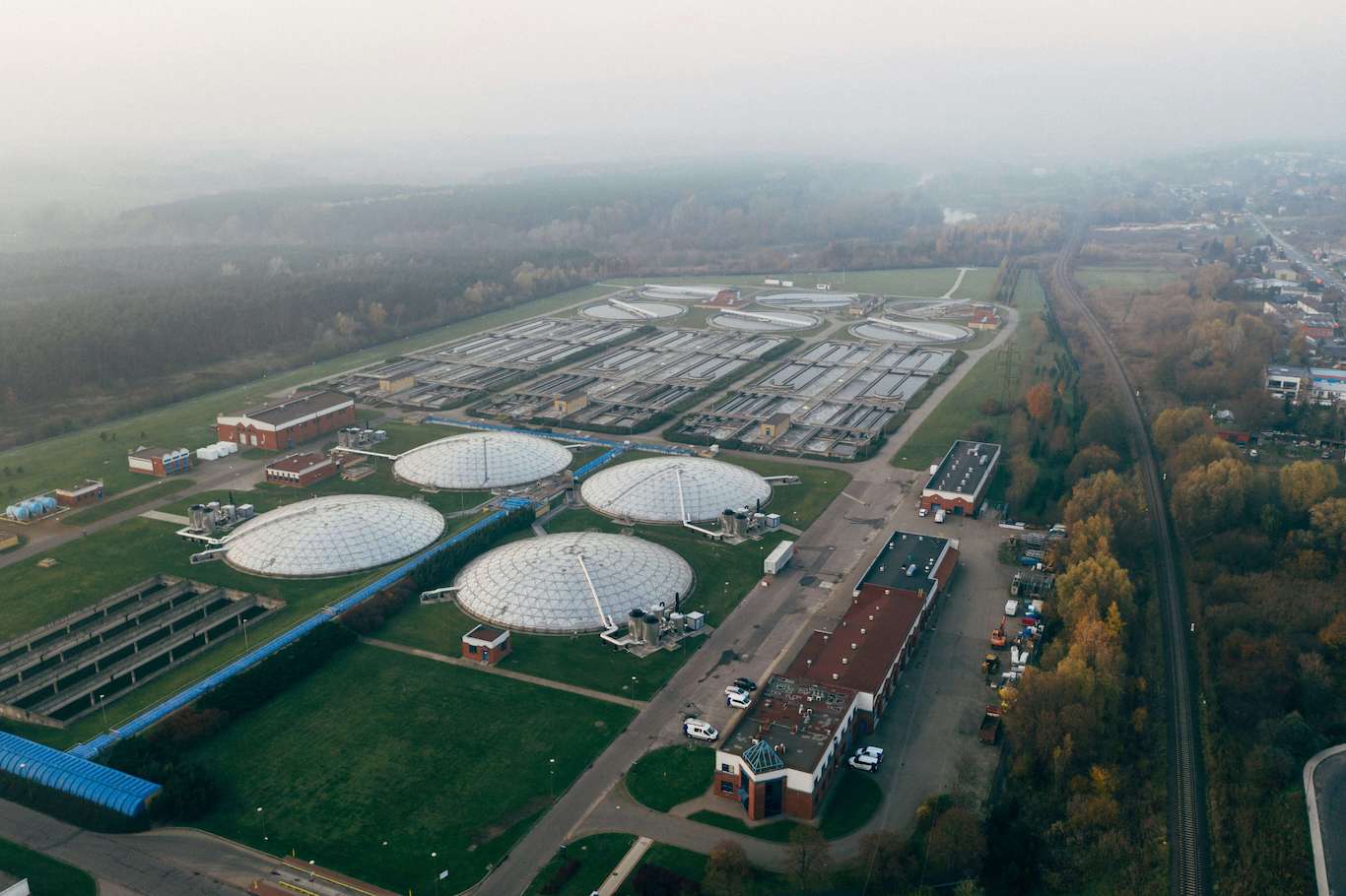 Aerial view of an industrial water treatment facility with distinctive dome-shaped structures, surrounded by roads and vegetation at dusk or dawn.